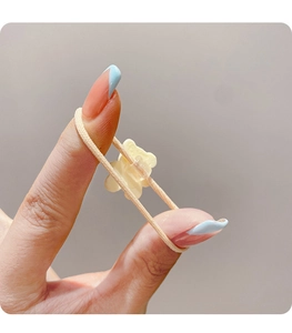 Detail shot of a cute beige elastic hair tie featuring a small translucent cartoon bear