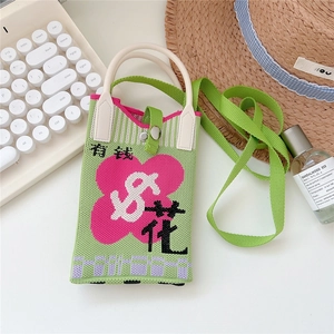 Close-up of green knit phone bag featuring pink flower design and unique woven patterns