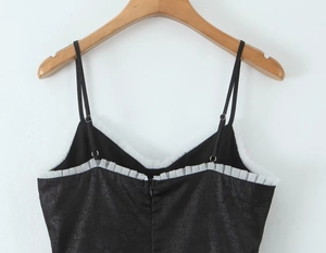 Détail du haut à bretelles noir avec volants en maille blanche et texture jacquard