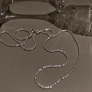 Close-up of silver-tone necklace featuring sparkling diamond-cut texture and lobster clasp