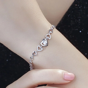 Close-up of heart-shaped silver chain bracelet with clear crystal on model's wrist