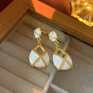 Détail macro de boucles d'oreilles vintage en émail blanc bordées d'or sur velours