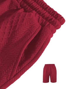 Detail of red knit shorts featuring textured geometric jacquard pattern and drawstring waist