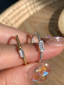 Macro detail of twisted S925 silver rings with square zircon in gold and silver finish