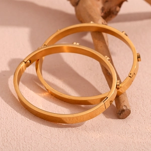 Detail of 18K gold plated stainless steel bangles with micro-studs on stone surface
