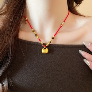 Primo piano di un ciondolo lucchetto dorato tradizionale su una collana in corda rossa