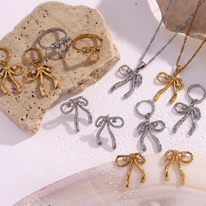 Detail of 18K gold plated bow jewelry set with sparkling rhinestones on textured stone