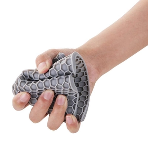 Flexible grey silicone trivet with honeycomb design being squeezed to show durability