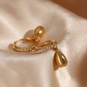 Elegant gold-plated hoop earrings with teardrop pendant on soft beige satin backdrop