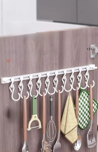 Detail showing white sliding cabinet hooks with kitchen tools on a dark wood door