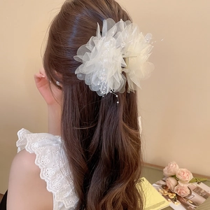 Elegant white mesh flower hair claw clip with pearl details on wavy brown hair