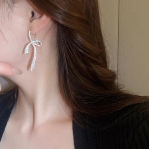 Detailed close-up of glittering bow earrings with silver plating on a female model