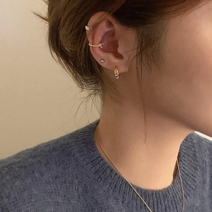 Close-up of minimalist gold heart earrings and necklace worn by model in blue sweater