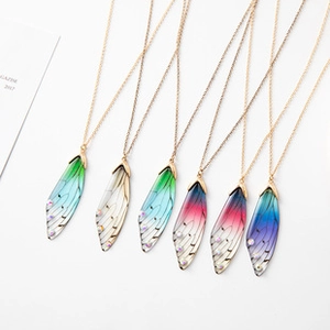 Macro detail of gradient cicada wing necklaces with shimmering crystals on fine gold chains