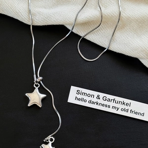 Macro shot of silver asymmetric star pendant with sleek snake chain on fabric