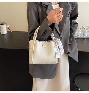 Detail of off-white lychee grain leather bucket bag with decorative plaid silk scarf bow