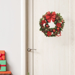 Couronne de Noël en pin avec nœud rouge et pommes de pin sur une porte en bois