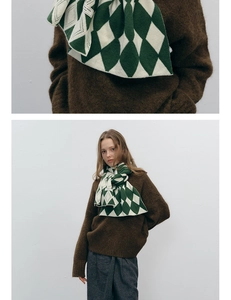 Detail of green and white diamond pattern knit scarf with artisan label and brown sweater
