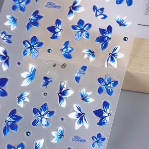 Macro shot of 3D embossed floral nail stickers featuring blue and white lilies