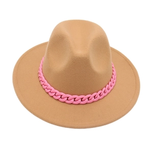 Detail of camel fedora hat featuring a bold pink acrylic decorative chain link on the brim