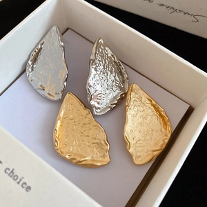 Close-up of gold and silver triangle earrings with hammer texture in a white gift box