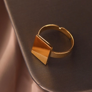 Macro di anello aperto geometrico dorato minimalista su sfondo di seta e metallo scuro