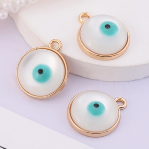 Macro shot of three golden circular evil eye pendants with white resin and teal accents