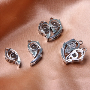 Detail of silver heart and water drop pendant charms with projection lens on orange silk