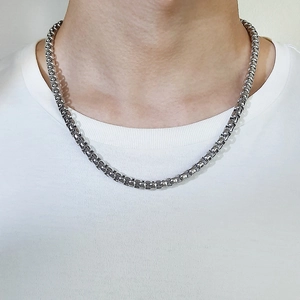 Gros plan sur un collier en acier titane argenté de 2 mm à 7 mm porté par un mannequin