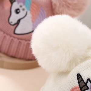 Detailed macro view of the soft faux fur pom-poms on the children's unicorn knit beanie