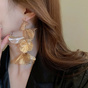 Macro shot of gold hollow layered flower tassel earrings with intricate metallic textures