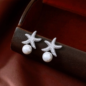 Macro detail of silver starfish earrings with cubic zirconia stones and round pearls