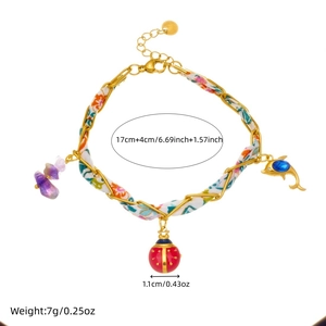 Bracelet chaîne en tissu fleuri avec pendentifs coccinelle et perles sur fond blanc