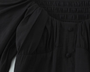 Détail de chemisier noir vintage avec texture smokée et boutons recouverts de tissu