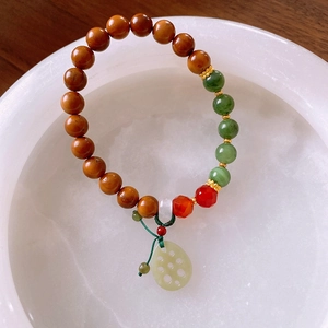 Macro detail of agate beaded bracelet featuring a green jade lotus root charm and cord