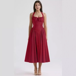 Sleeveless red halter dress with corset bodice and pleated skirt against studio background