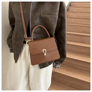 Brown retro small square handbag with gold buckle shown on a model on a staircase