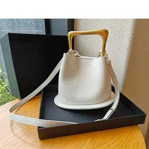 White leather bucket bag with gold irregular metal handle in black gift box