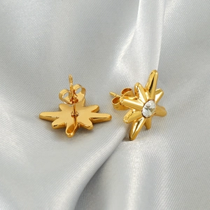 Modern eight-pointed star gold stud earrings with white zircon on silk fabric