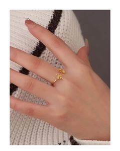 Detail shot of a delicate gold bee ring with an adjustable open band on a finger