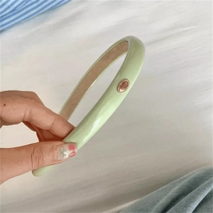 Close-up of light green PU leather headband with metallic oval plaque and inner padding
