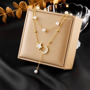 Close-up of double-layer necklace with pearls, star and moon pendants on beige jewelry box