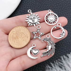 Detailed size comparison of vintage sun, moon, and star charms next to a 1 dollar coin