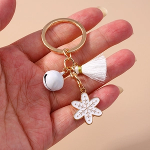 Detail showing white bell, tassel and gold snowflake charm on a Christmas keychain