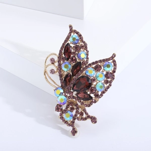 Detailed close-up of golden butterfly brooch with purple and iridescent rhinestones