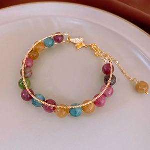 Detailed close-up of colorful beads and golden butterfly pendant on handmade bracelet