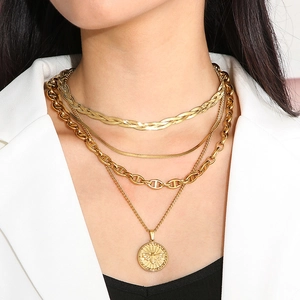 Close-up of layered gold butterfly and coin necklace on model with white blazer