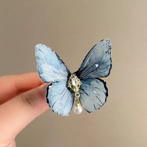 Detail of blue gradient butterfly hair clip with rhinestones and a white hanging pearl