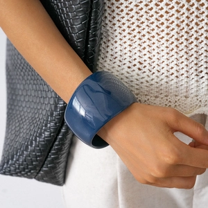 Close-up of a wide dark blue resin geometric bangle worn on a woman's wrist