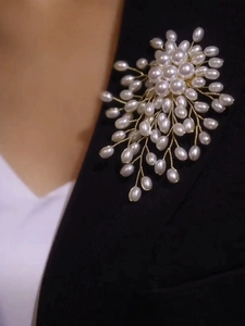 Close-up of a luxury snowflake pearl brooch on a classic black and white suit